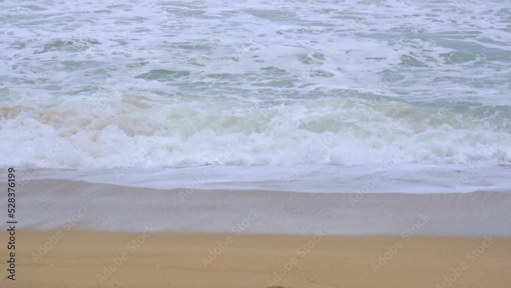 Ocean waves and sand on the beach of tropical seas in Thailand. Strong sea waves crash to shore in the rainy season. Ocean waves and sand on the beach of tropical seas in Thailand. Strong sea waves crash to shore in the rainy season.