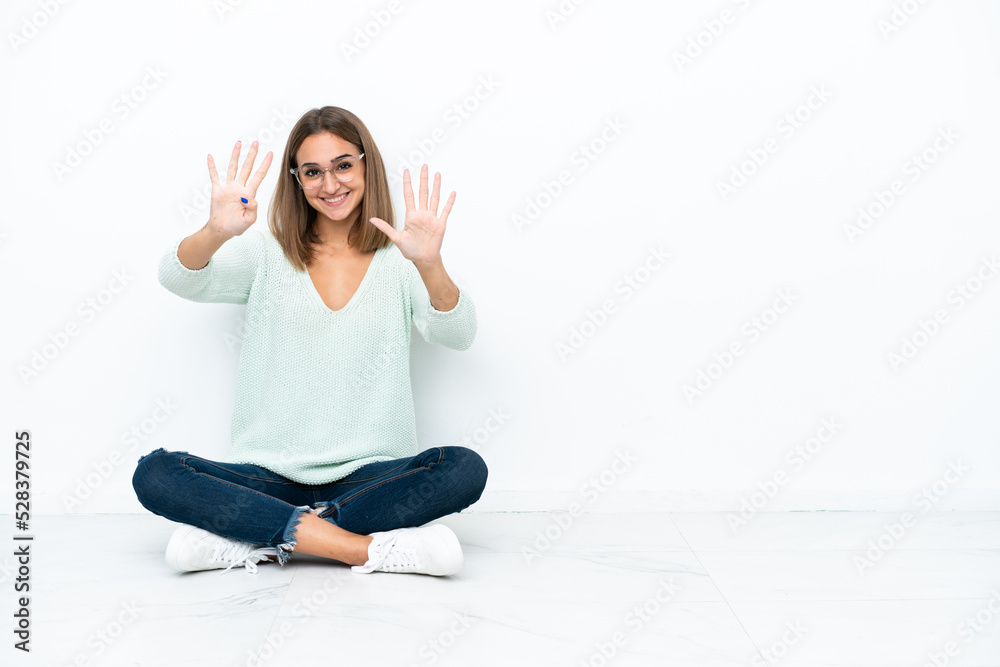 Young caucasian woman sitting on the floor isolated on white background counting nine with fingers Young caucasian woman sitting on the floor isolated on white background counting nine with fingers