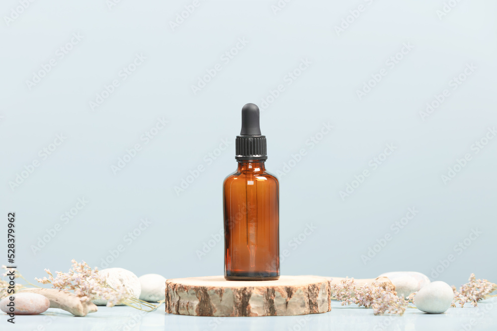Amber glass transparent bottle on wooden podium with natural stones and plants