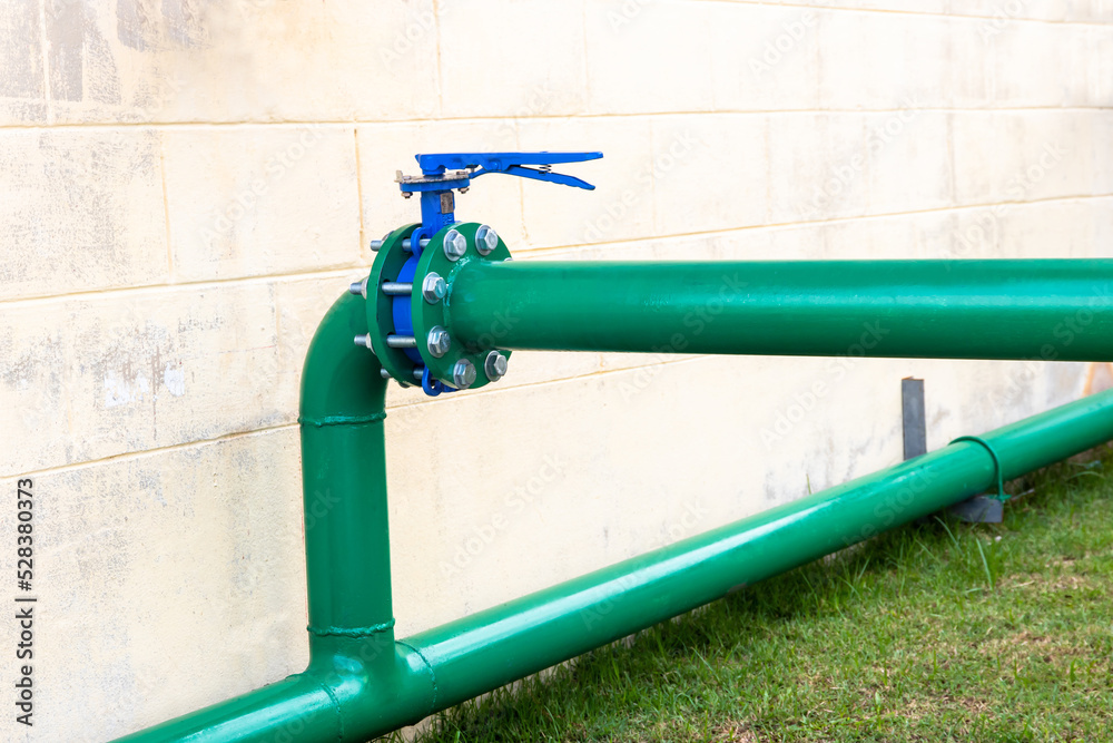 Green piping and big valve for water supply system in industry. Pipes ...