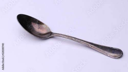 Frosted retro spoon is spinning on the table, video of cutlery white background