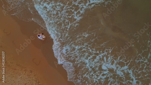 Aerial of a romantic couple slow dancing at the Kilyos beach while the foamy waves hit the sand photo
