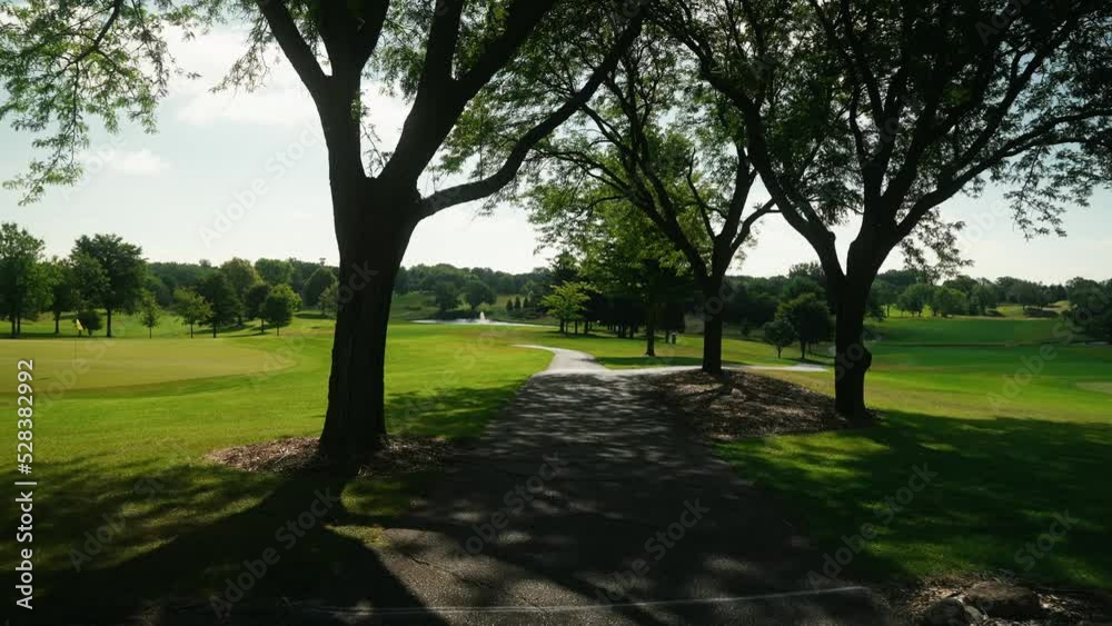 walking down a cart path shaded by surrounded trees on a golf course at a country club walking down a cart path shaded by surrounded trees on a golf course at a country club