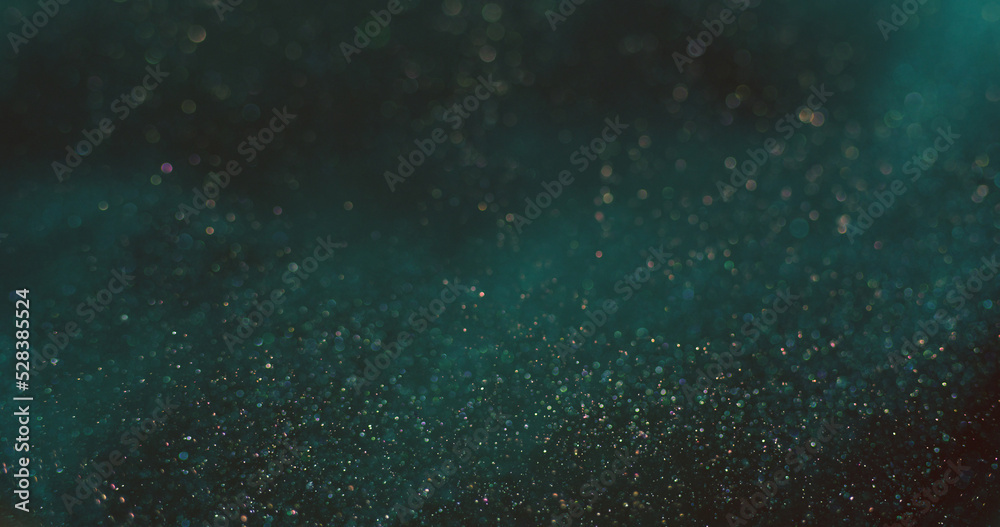 Bokeh light background. Shiny particles texture. Cosmic stardust. Defocused blue orange color shimmering glitter circles on dark abstract wallpaper.