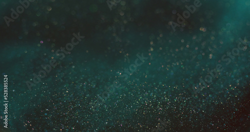Bokeh light background. Shiny particles texture. Cosmic stardust. Defocused blue orange color shimmering glitter circles on dark abstract wallpaper.