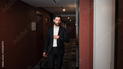 Wallpaper Mural A man in a classic suit with a suitcase walks down the corridor in the hotel, approaches the door and takes out the electronic key for opening door. Businessman arriving in hotel for business trip. Torontodigital.ca