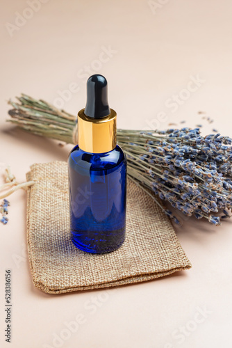 Lavender oil or serum and lavender flowers on beige backgrund. Skincare cosmetics products. Natural spa beauty products. Lavender essential oil  serum  massage oil  liquid. Mockup