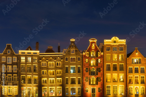 Damrak, Amsterdam, Netherlands. View of houses during sunset. The famous Dutch canals. A cityscape in the evening. Travel photography.