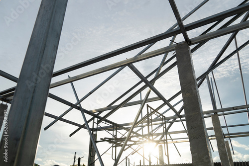 Steel roof structure connected to cement columns under the sky. with sunlight in the evening.