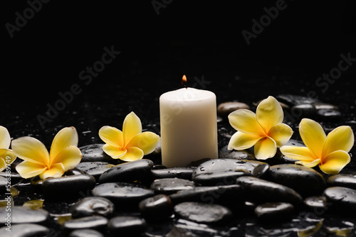 spa still life of with yellow frangipani and  green plants leaves white candle  with reflection 