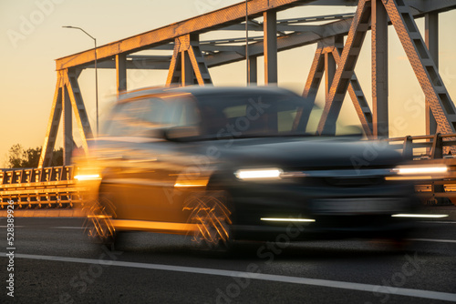 Blured car driving over a bridge at sunset