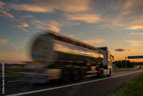 Fototapeta Naklejka Na Ścianę i Meble -  Blured  tanker truck driving along a highway at sunset
