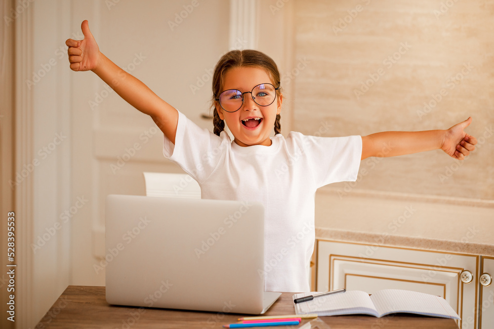 Smiling little caucasian girl having video call in remote classroom with teacher using laptop at desk at home, happy little kid greeting with tutor, learning online on computer, home learning concept Smiling little caucasian girl having video call in remote classroom with teacher using laptop at desk at home, happy little kid greeting with tutor, learning online on computer, home learning concept