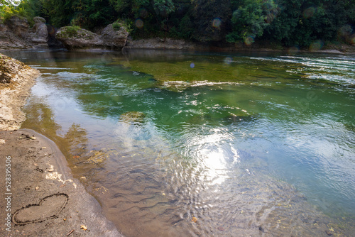 a beautiful landscape with a mountain river and a heart painted on the sand on a summer day