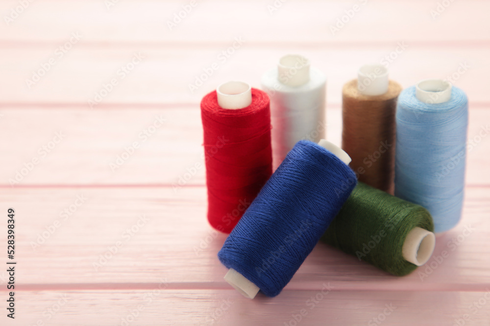 Color sewing threads on wooden pink background Color sewing threads on wooden pink background