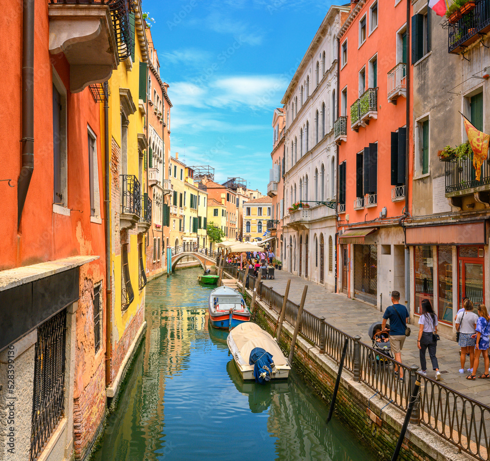 View on the narrow cozy streets of the canals with parked boats in Venice, Italy. Architecture and landmark of Venice.