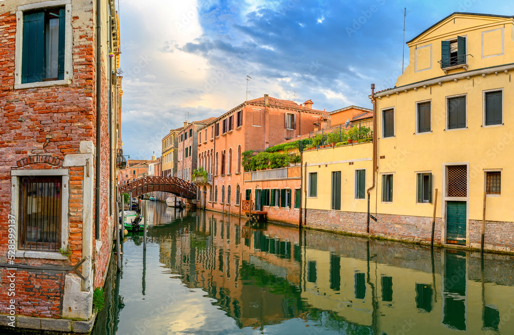 View on the narrow cozy streets of the canals with parked boats in Venice, Italy. Architecture and landmark of Venice.