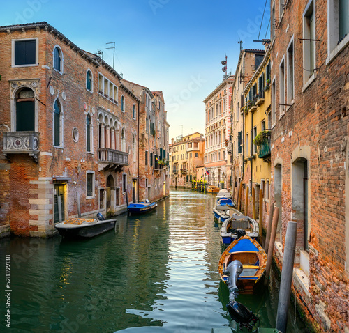 Fototapeta Naklejka Na Ścianę i Meble -  View on the narrow cozy streets of the canals with parked boats in Venice, Italy. Architecture and landmark of Venice.