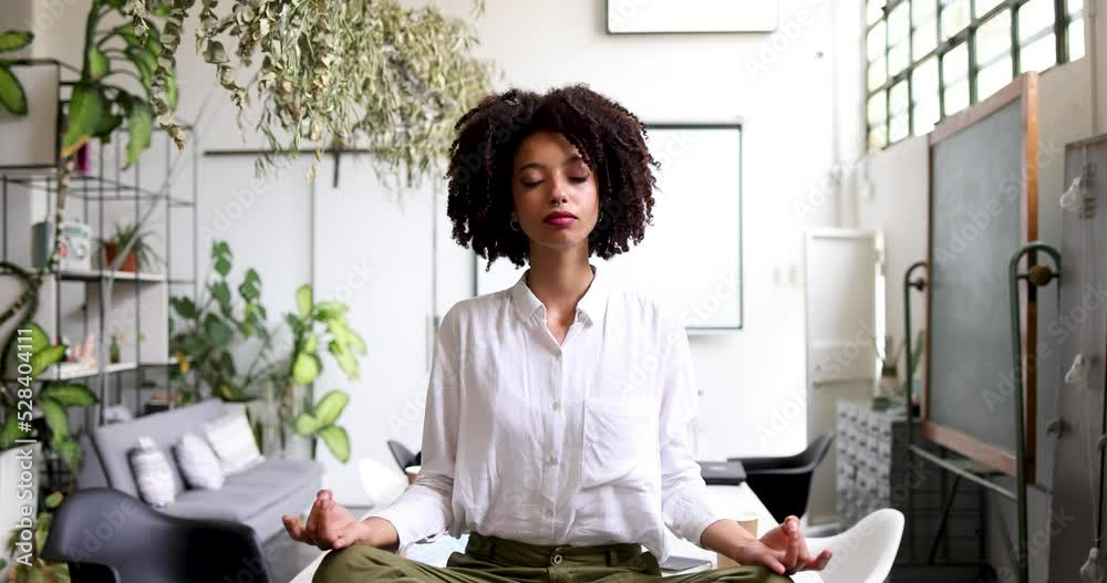 Young businesswoman meditating cross-legged on office table Young businesswoman meditating cross-legged on office table