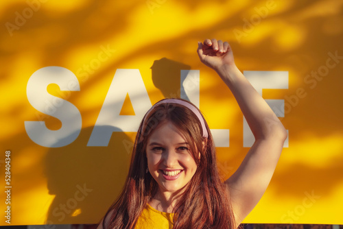 Happy woman with hand raised in front of sale sign photo