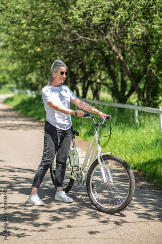 Good -looking mature woman with a bike in the park