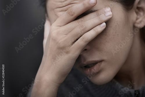 Depressed woman covering eyes with hand photo