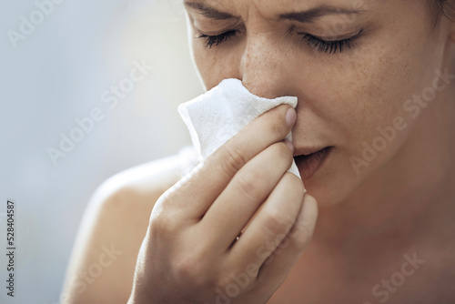 Ill woman blowing nose with tissue paper