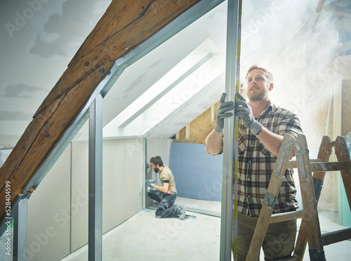 Construction worker measuring metal for drywall at site