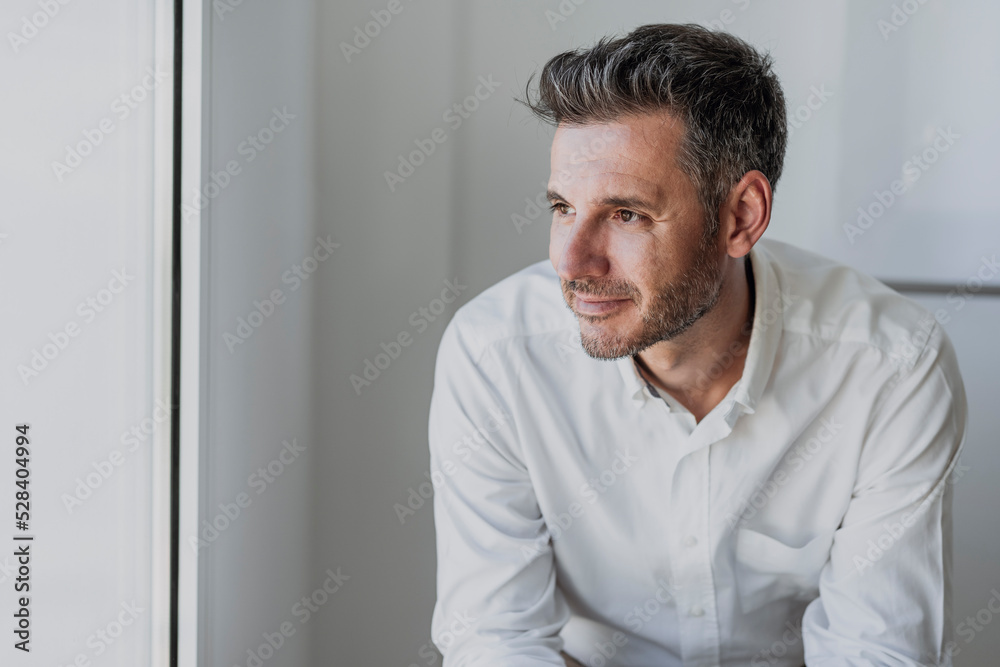 Smiling thoughtful businessman in front of white wall Smiling thoughtful businessman in front of white wall