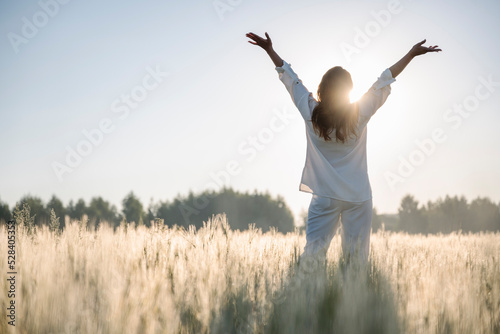 Woman with arms raised standing in cornfield photo