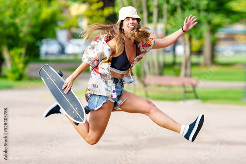 Carefree woman with skateboard jumping at park photo
