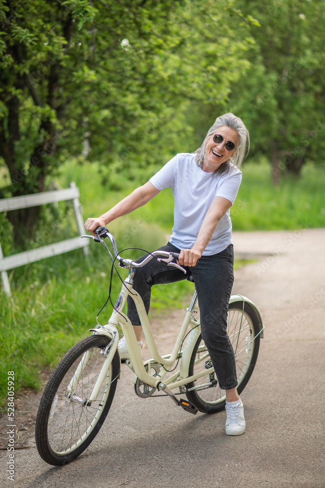 A woman in sportswear with a bike in the park feeling cheerful A woman in sportswear with a bike in the park feeling cheerful