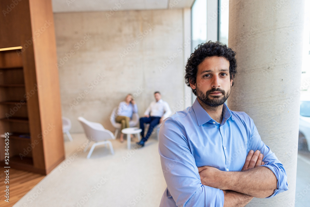 Confident professor with arms crossed leaning on column Confident professor with arms crossed leaning on column