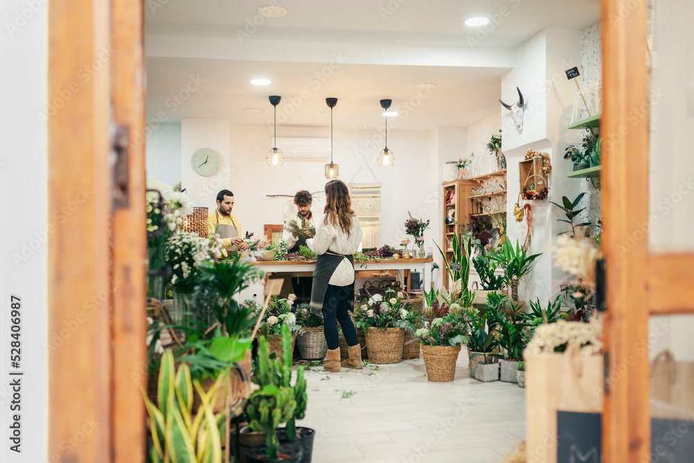 Florists working in flower shop seen though doorway Florists working in flower shop seen though doorway