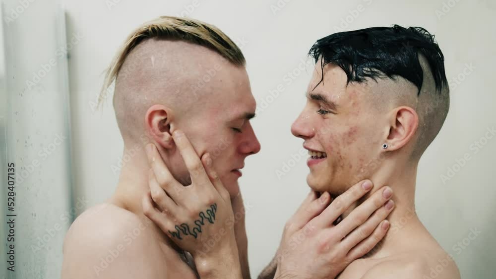 Wet gay couple hugging each other kissing on the lips