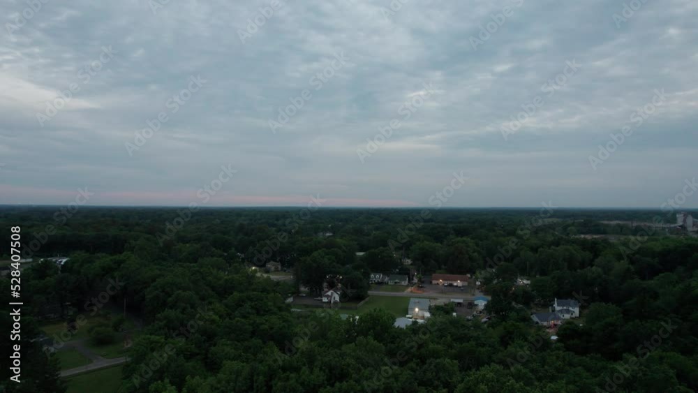 Aerial drone shot over houses in the small town during sunset on a cloudy evening. Aerial drone shot over houses in the small town during sunset on a cloudy evening.