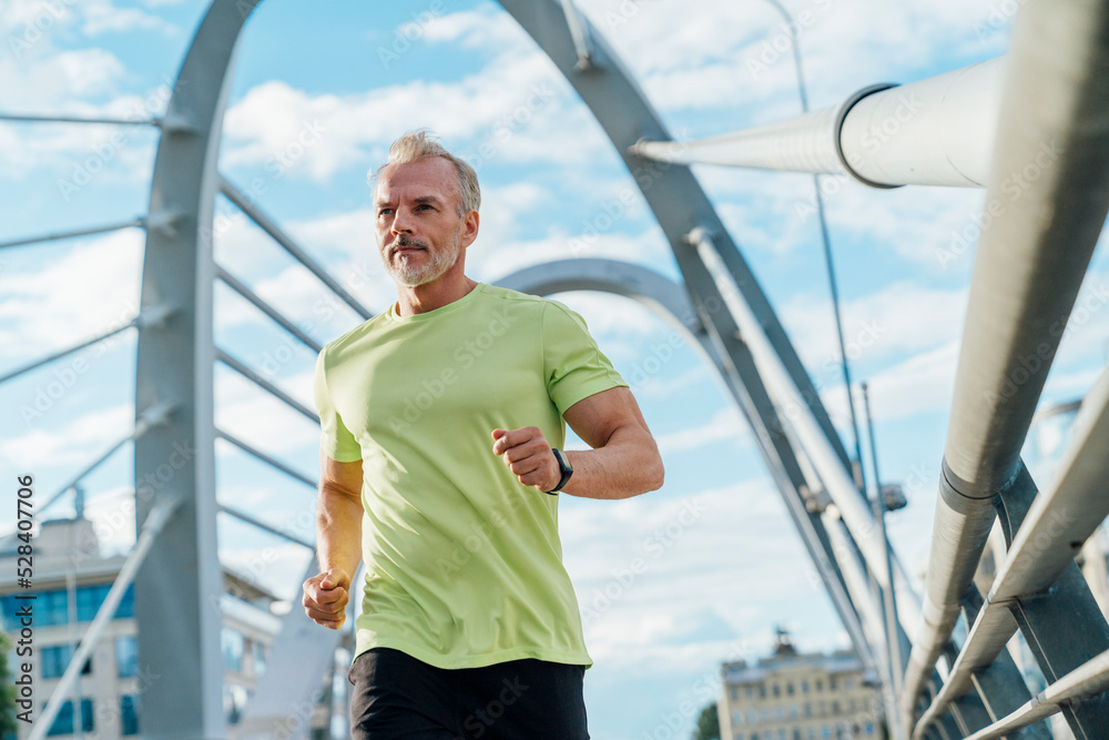 Man running on suspension bridge in city