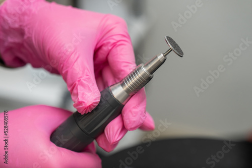 Woman on professional pedicure procedure by abrasive disc machine in beauty salon. 
