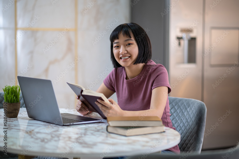 Pretty young asian girl reading a book and looking involved Pretty young asian girl reading a book and looking involved