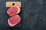 Steaks. Fresh Filet mignon Steaks with spices rosemary and pepper on black marble board on gray background. Top view.