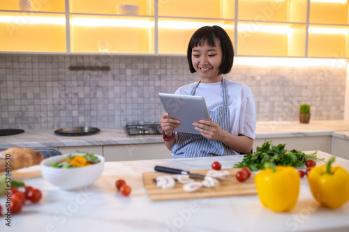 A girl in the kitchen reading a cookery blog online