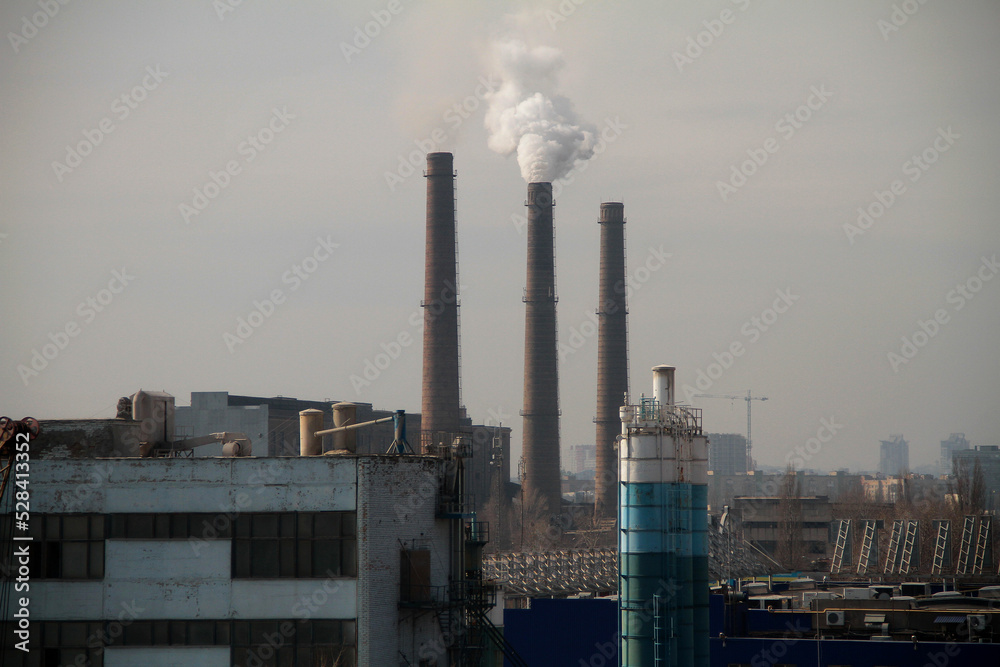 Clouds of smoke from the smokestacks of an industrial plant pollutes the air in a suburban area
