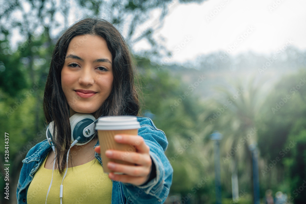 smiling young girl with headphones and takeaway in the park smiling young girl with headphones and takeaway in the park