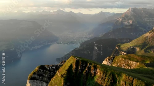 Spinning flyover around the summit of Niederbauen Chulm on a golden summer morning in the Swiss Alps with a view of the fjords of Lake Lucerne, Mythen, Rigi, Burgenstock, Pilatus  (sped up 4x) photo