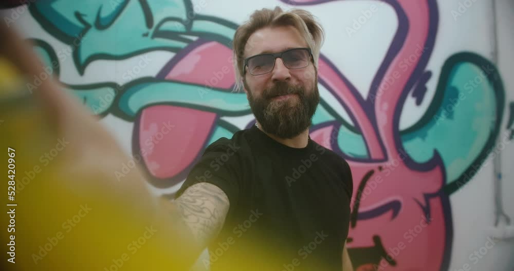Portrait of a graffiti artist painting on glass. handheld camera
