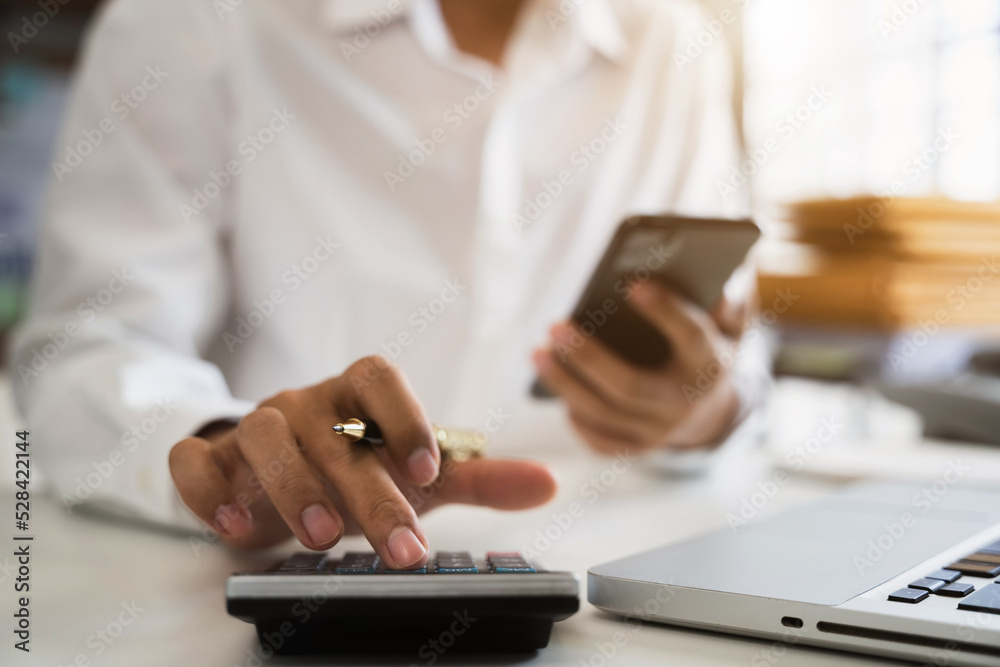 Businessman using calculator and smartphone  to analysis graph company financial in office.