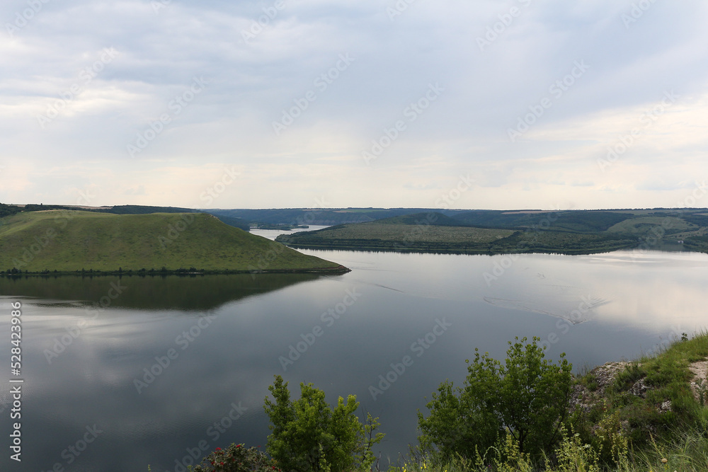 The panoramic landscape of Bakota Bay view. The banks of a large river with smooth calm water. Ukraine, Dniester river.