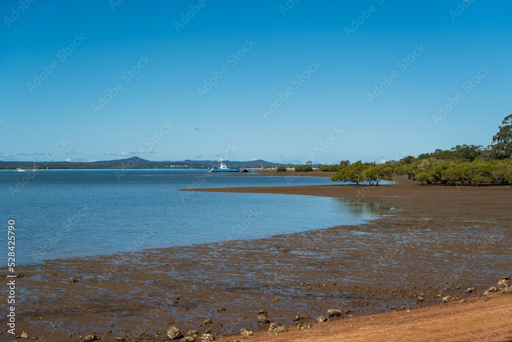 View from the shoreline at low tide across to Macleay Island, and Stradbroke Island in the distance. Vehicular ferry. Redland Bay, Queensland, Australia. View from the shoreline at low tide across to Macleay Island, and Stradbroke Island in the distance. Vehicular ferry. Redland Bay, Queensland, Australia.