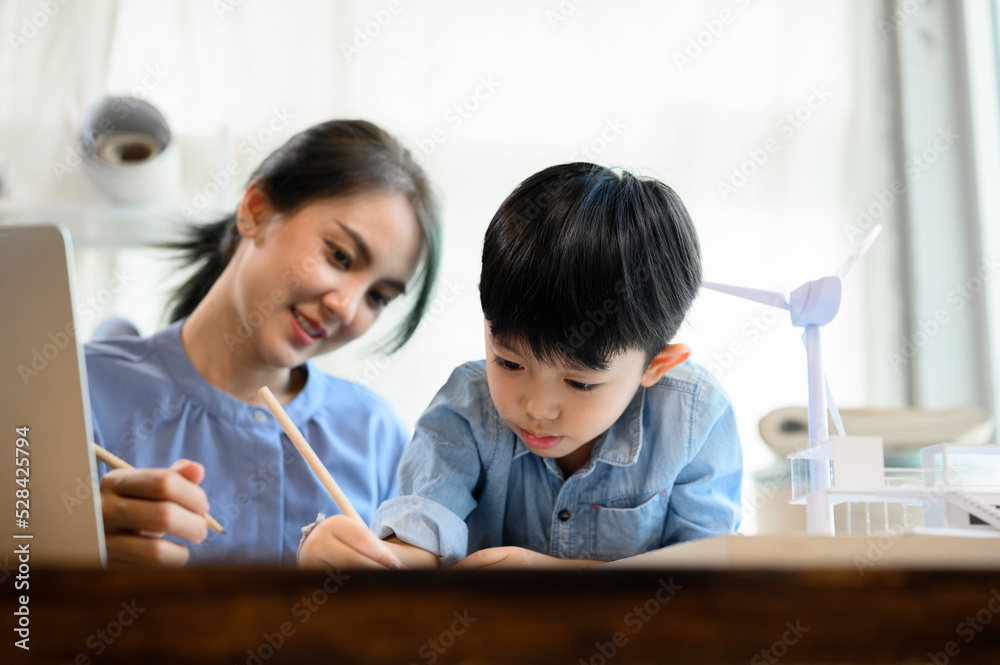 Little kid son practicing pencil drawing and writing under mother's control, While Young Asian mother is an architect spending time with her little kid son, Mother helping son, Homeschool concept Little kid son practicing pencil drawing and writing under mother's control, While Young Asian mother is an architect spending time with her little kid son, Mother helping son, Homeschool concept