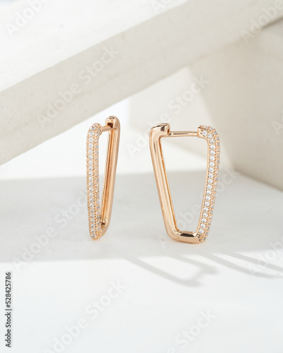 Golden earrings with white crystals and diamonds. Beautiful earrings on white background. Women accessories. Fashionable jewelry.